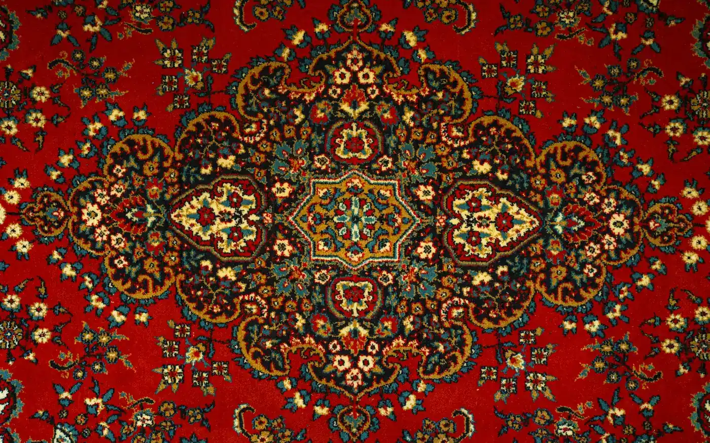 A deep red silk carpet with an ornate central medallion